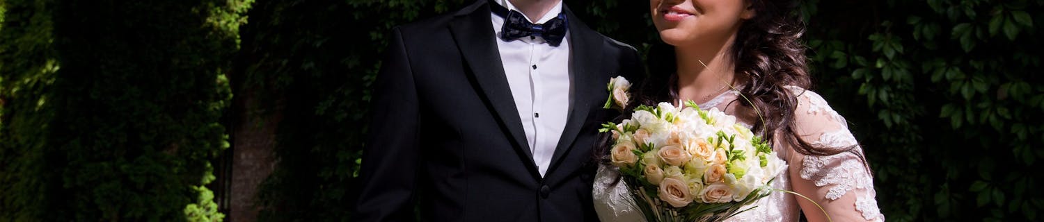 Brudepar fotograferet i direkte sollys med rodet baggrund